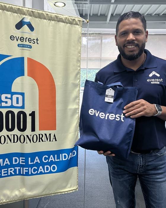 Aramis Monge junto al pendón de la certificación ISO 9001 de FONDONORMA